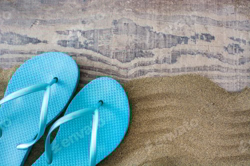 Preview: Turquoise flip-flops resting on sandy beach by wooden boardwalk