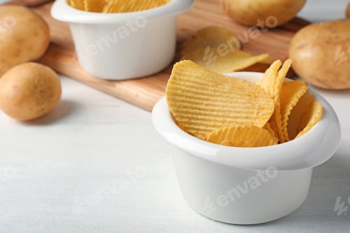 Preview: Bowl of crispy potato chips on white wooden table. Space for text