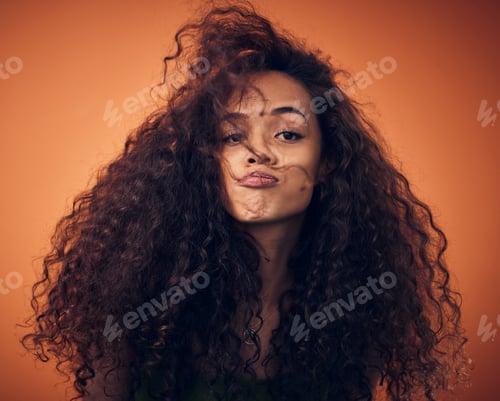 Preview: Shot of a woman with curly hair posing against an orange background