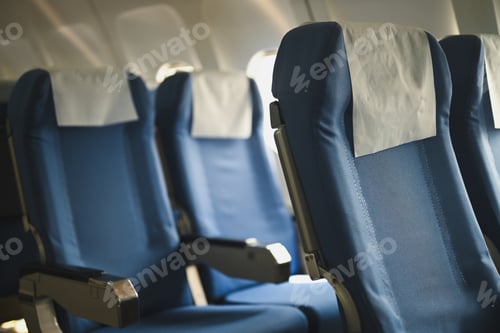 Preview: Seats of an airplane with natural light streaming in through the windows.