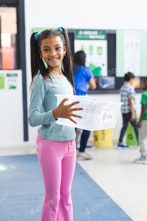 Preview: Biracial girl holding plastic recycling container in school classroom