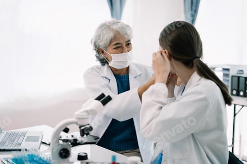 Preview: Team of biochemical research scientists working with a microscope