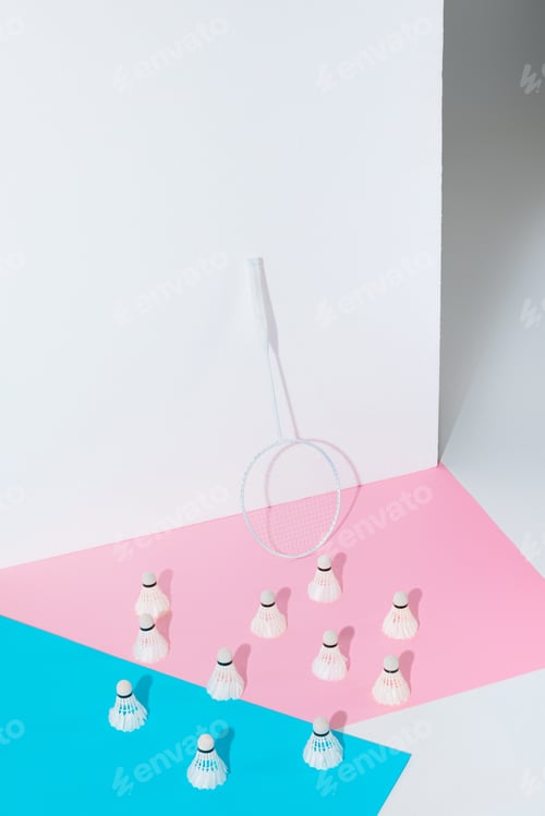 Preview: badminton racket and shuttlecocks on blue and pink papers at wall