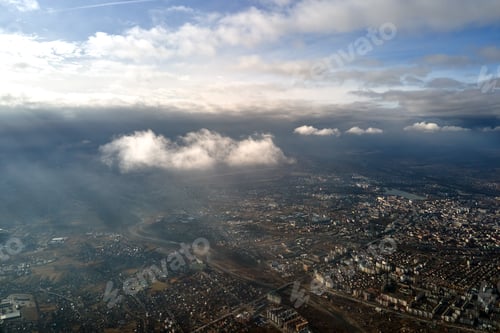 Preview: Aerial view from high altitude of distant city covered with puffy cumulus clouds