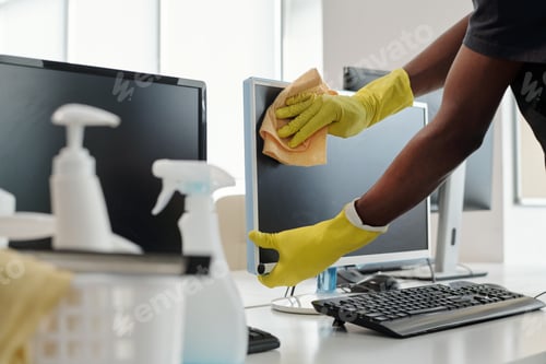 Preview: Gloved hands of young African American man with duster wiping computer screen