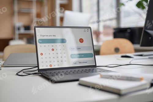 Preview: Close-up of Laptop at Workplace Table in Office with Calendar Page on Screen
