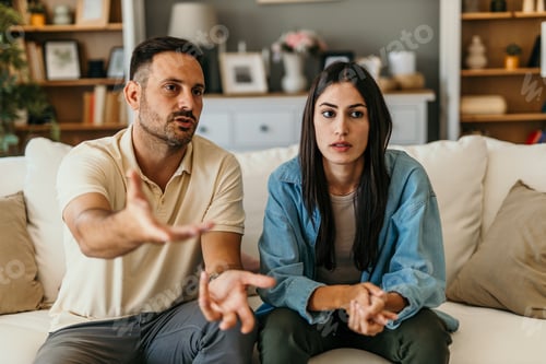 Preview: Couple having serious discussion sitting on sofa at home