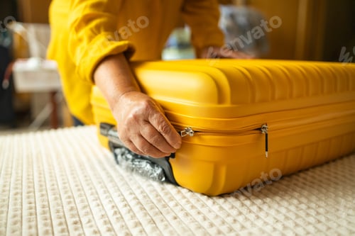 Preview: Close-up of senior male hands packing and locking bag for holidays trip. Female preparing travel