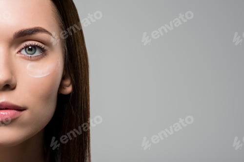 Preview: close-up portrait of young woman with moisturizing cream on face isolated on grey