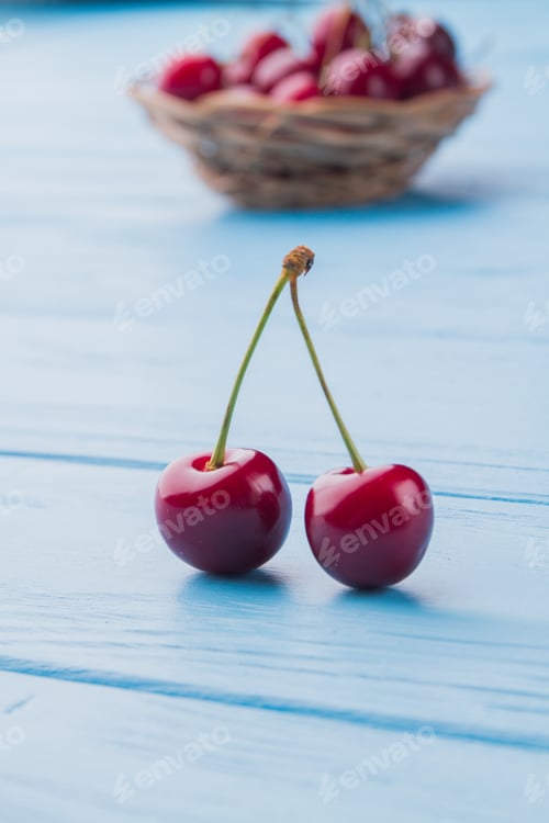 Preview: Two ripe fresh cherries and wicker plate on the background.