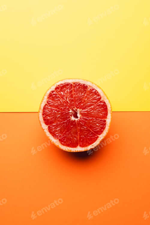 Preview: Close up of half of red grapefruit and copy space on orange and yellow background
