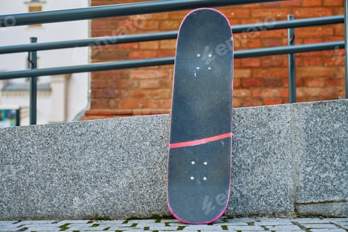 Preview: Used pink skateboard against stone wall in urban setting