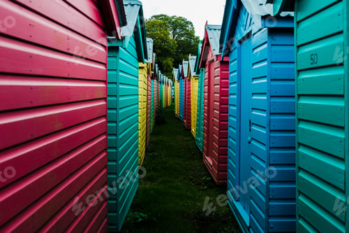 Preview: Colorful bathing cabin or beach hut rows on a grassy ground in the summertime
