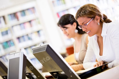 Preview: Female Students Researching At The Library On Computers