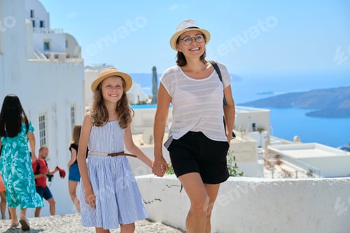 Preview: Happy tourists family mother and daughter kid walking on the Greek island of Santorini