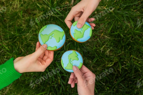 Preview: Earth Day concept. Hands hold gingerbread in the shape of the Earth. Care for the environment.