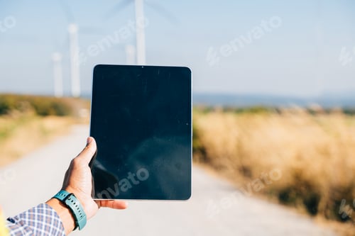Preview: Engineer with tablet at windmill farm