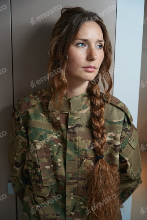 Preview: Woman in a camouflage uniform stands by the closet in the room