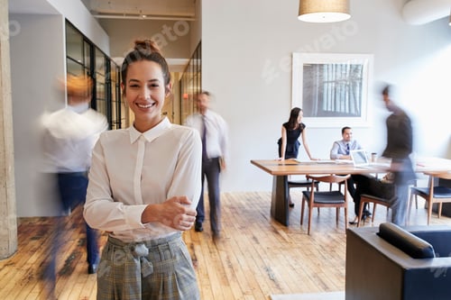 Preview: Portrait of young white woman in a busy modern workplace