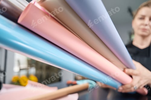 Preview: Florist holds lot of multi-colored paper for bouquet of flowers.