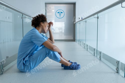Preview: African american female doctor sitting in hospital corridor taking rest