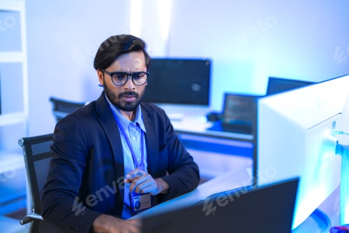 Preview: Focused Indian male AI developer coding a complex machine learning algorithm late