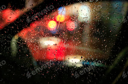 Preview: The lights of the night city through the glass with raindrops