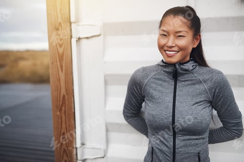 Preview: Smiling Asian woman in sportswear standing outdoors before a run