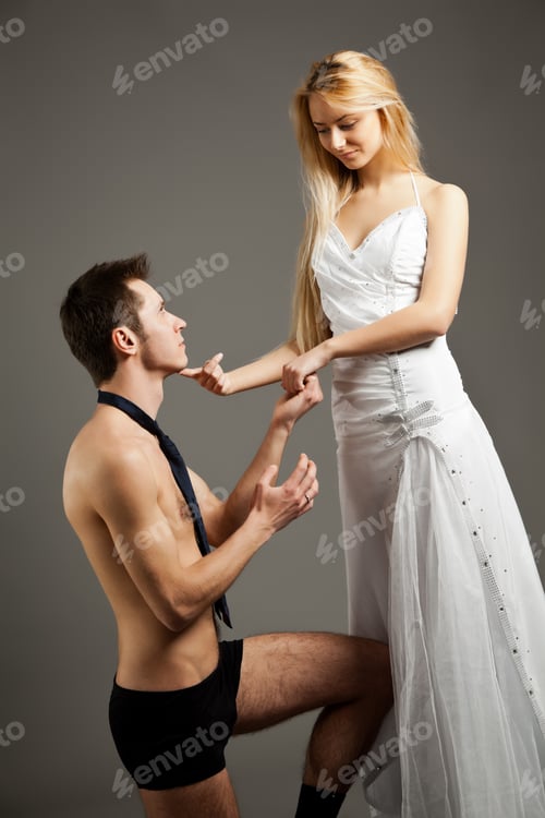 Preview: Young woman in wedding dress standing and touching man in underwear