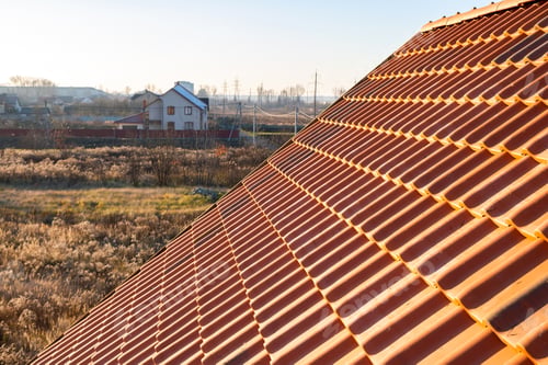 Preview: Overlapping rows of yellow ceramic roofing tiles covering residential building roof.