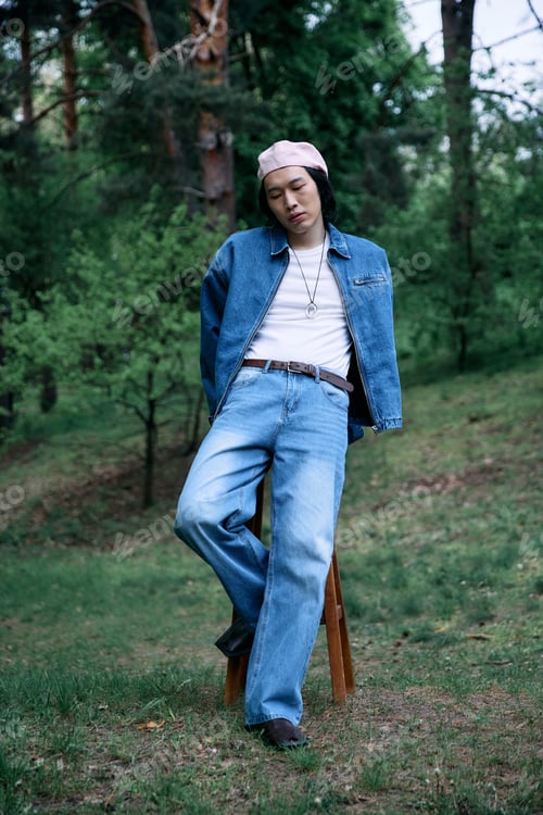 Preview: Stylish young man in denim enjoying a tranquil moment in the park during the afternoon