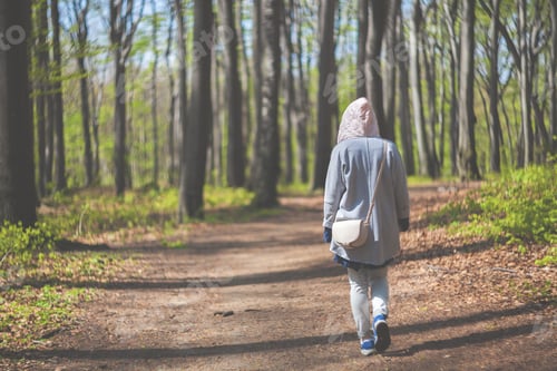 Preview: Young woman walking alone in early spring forest