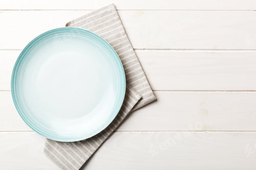 Preview: Top view on colored background empty round blue plate on tablecloth