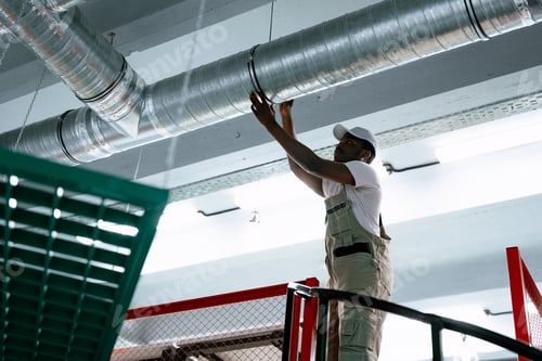 Preview: Worker installs metal duct in commercial building during renovation process in urban environment