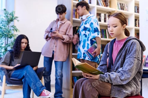 Preview: Asian Girl Reading Book in Library with Group of Students