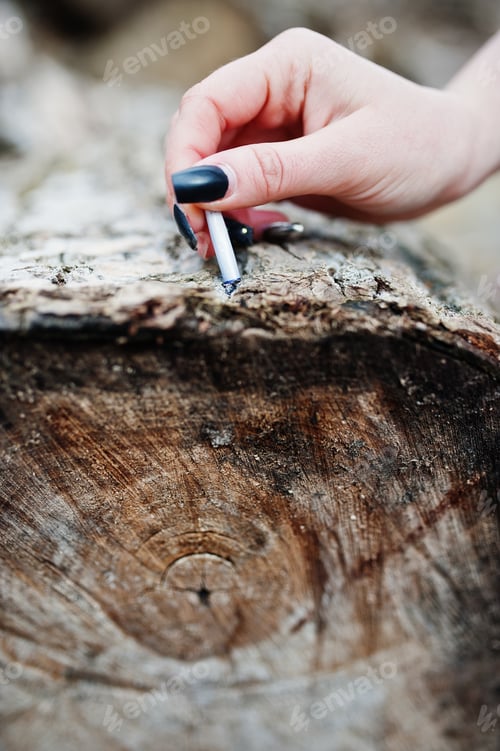 Preview: Hand of girl with extinguished cigarette on stump. Stop smoking social problem.