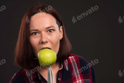 Preview: Female model in fall winter collection outfits biting a green apple on the knife