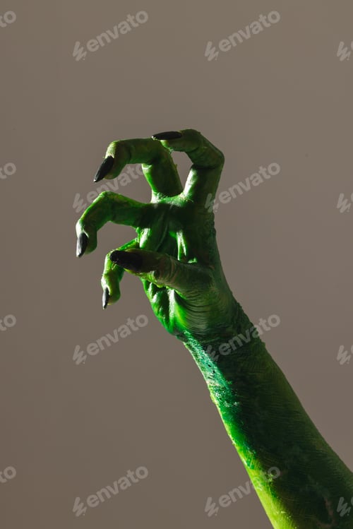 Preview: Vertical image of green monster hand with black nails making gesture on grey background