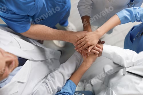 Preview: Young medical doctors putting hands together indoors, top view. Unity concept