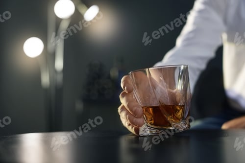 Preview: Man holding glass with whiskey at table, closeup. Space for text