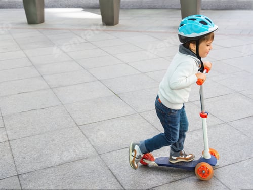 Preview: Toddler in helmet is riding scooter on parking lot with parked bicycles. Urban vehicle for children