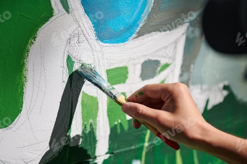 Preview: Girl artist hand holds paint brush and draws green nature landscape on canvas