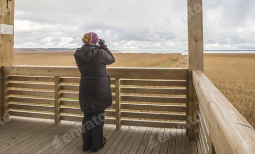 Preview: Woman watching the winter sea and deserted landscapes with binoculars