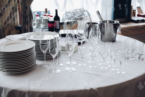 Preview: Assortment of kitchenware on white table.View over white round table with stacks of white plates