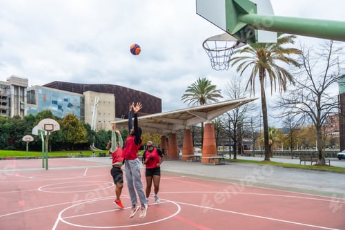 Preview: People playing basketball outdoors in urban city park