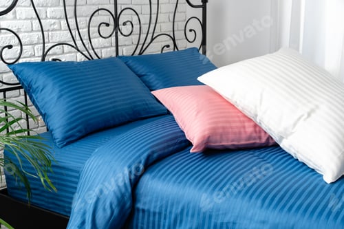 Preview: Blue Striped Bedding With Pink and White Pillows on a Bed With Black Iron Headboard