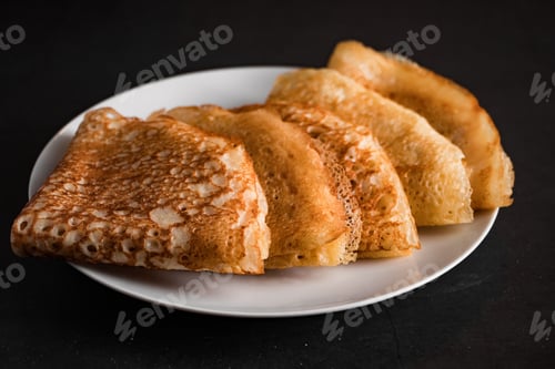 Preview: A stack of thin pancakes on a dark wooden background. A traditional dish of crepes for the holiday
