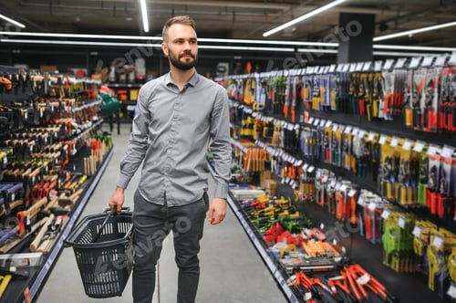 Preview: male builder in a hardware store chooses a tools