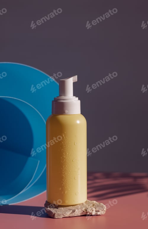 Preview: Yellow bottle with a dispenser on a stone on a pink background.