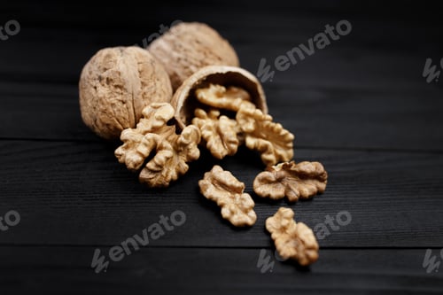 Preview: Walnut and walnut kernels and whole walnuts on rustic black wooden background.